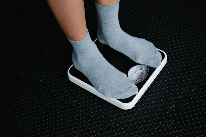 Weight management with a person checking body weight on a bathroom scale